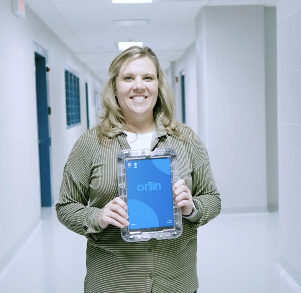 Crystal Petty in a hallway, holding up an Orijin laptop.